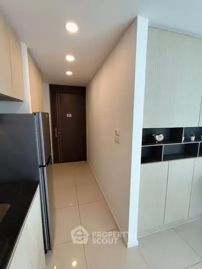 Modern kitchen with sleek cabinetry and stainless steel fridge in a compact apartment layout.