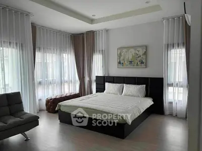Spacious bedroom with modern decor and large windows for natural light.