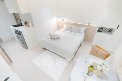 Chic studio apartment with modern decor, cozy bed, and compact kitchen area, perfect for urban living.