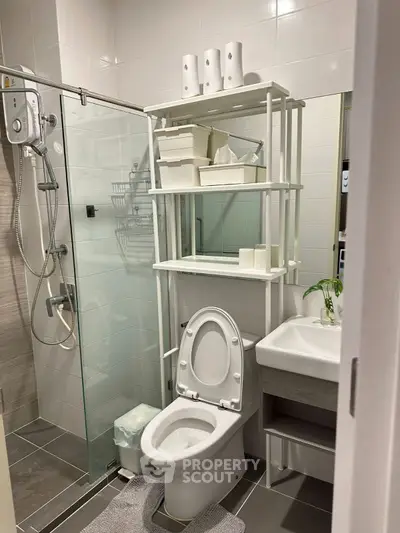 Compact modern bathroom with glass shower and sleek storage solutions.