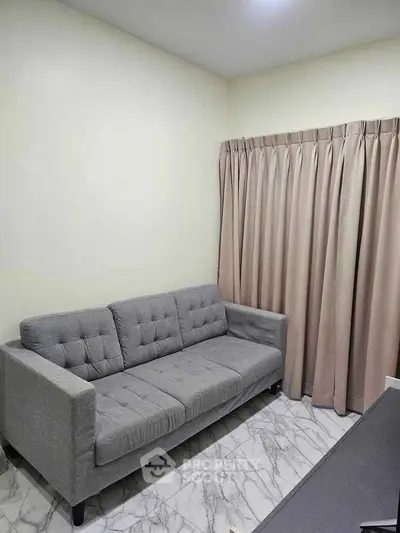 Cozy small living room with a gray sofa and elegant curtains.