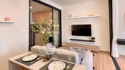 Modern living room with open kitchen, stylish decor, and wall-mounted TV in a cozy apartment.