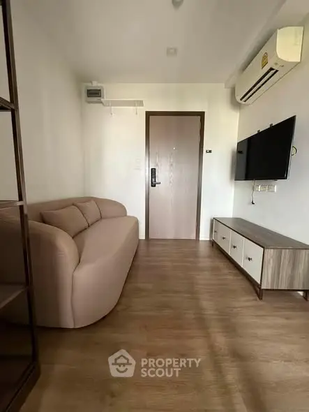 Modern living room with sleek furniture and wall-mounted TV in a cozy apartment.