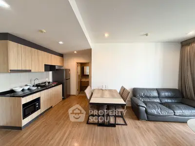 Modern open-layout kitchen and living room with sleek furniture and wooden flooring.