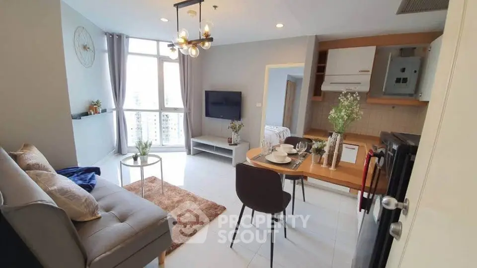 Modern living room with open kitchen, stylish decor, and city view from large windows.
