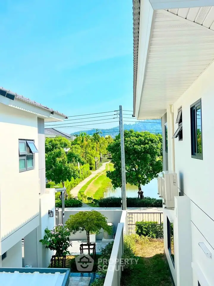 Stunning view from modern home balcony overlooking lush greenery and serene pathway.