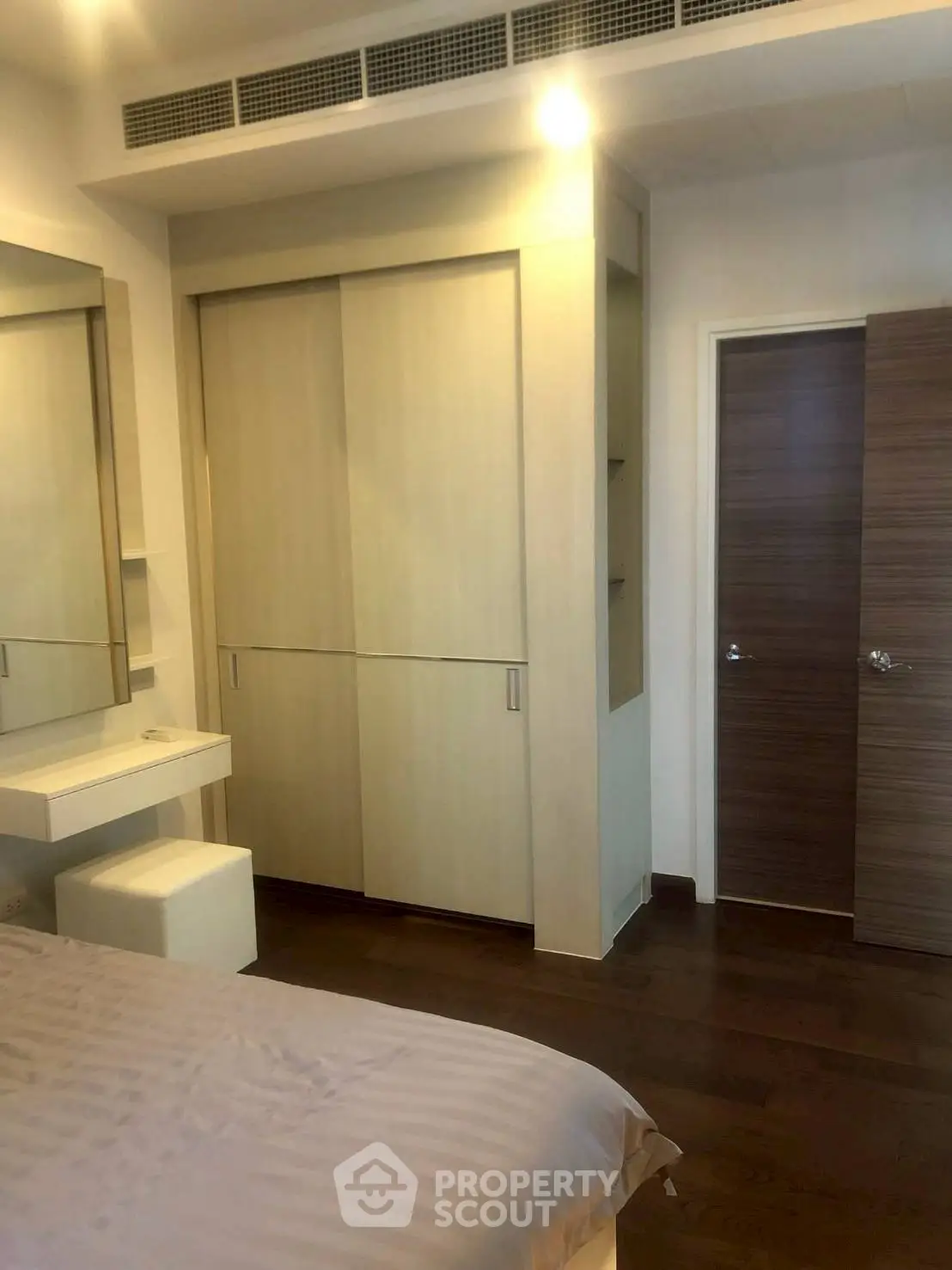 Modern bedroom with sleek wooden flooring and built-in wardrobe, perfect for stylish living.