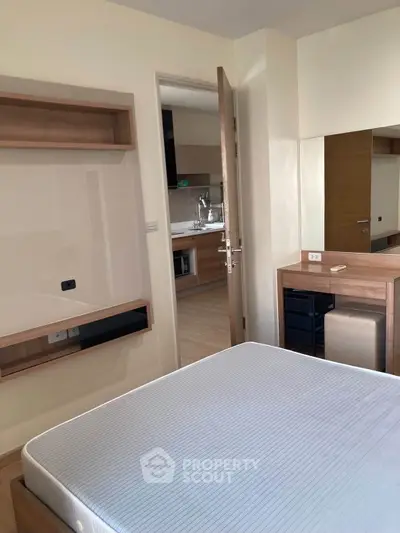 Modern bedroom with sleek furniture and view into a stylish kitchen, perfect for urban living.