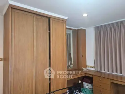 Spacious bedroom with built-in wooden wardrobe and desk, perfect for organized living.
