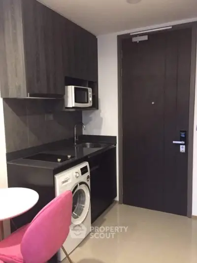 Compact modern kitchen with washing machine and microwave in stylish apartment