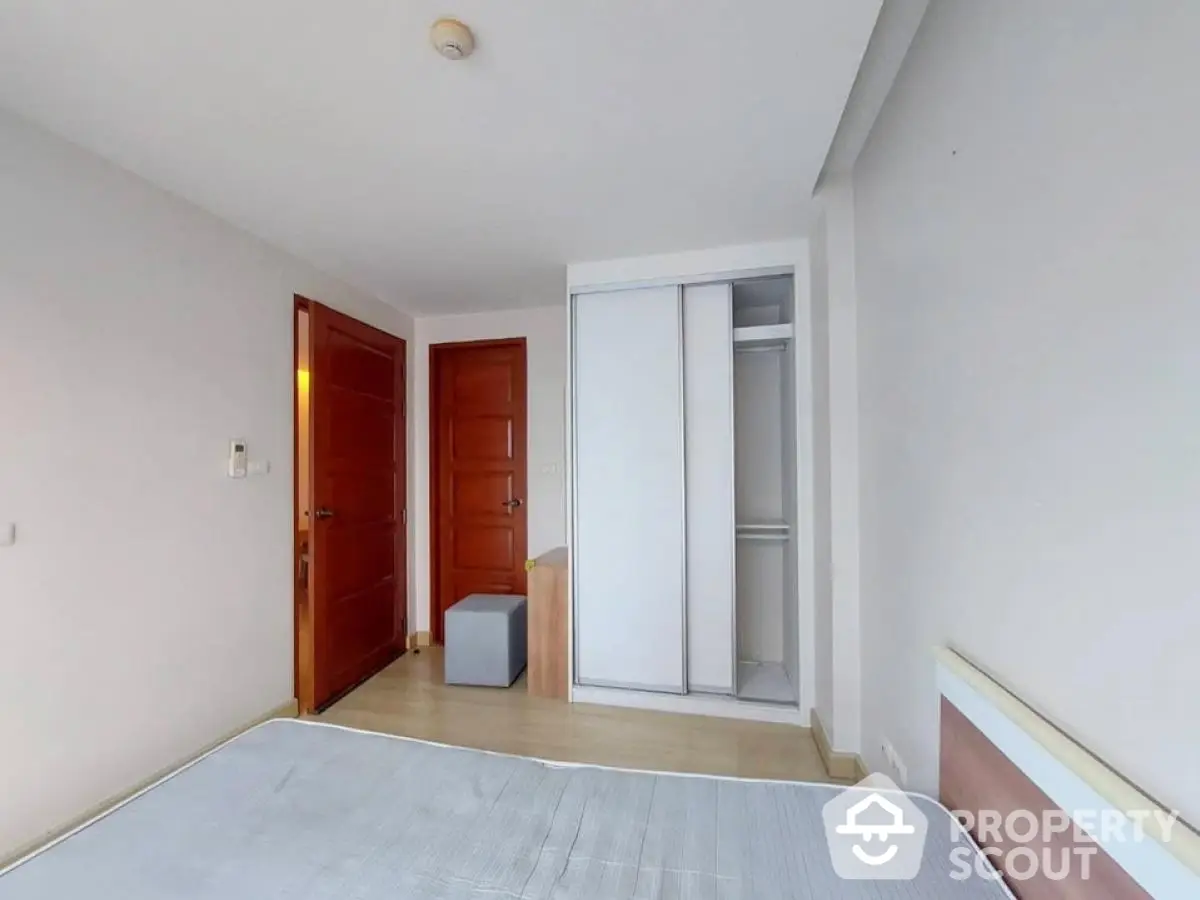 Spacious bedroom with modern closet and wooden doors in a minimalist design.