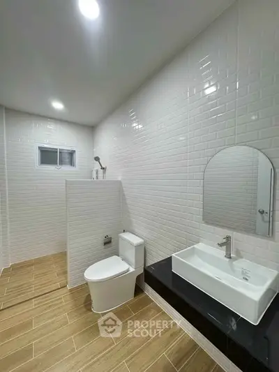 Modern bathroom with sleek design, featuring white tiles, a stylish sink, and a contemporary toilet.