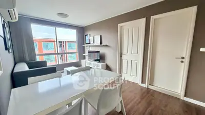 Modern living room with sleek furniture and large window offering natural light.