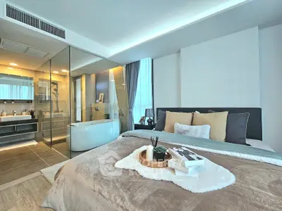 Luxurious bedroom with ensuite bathroom featuring glass walls and modern decor.