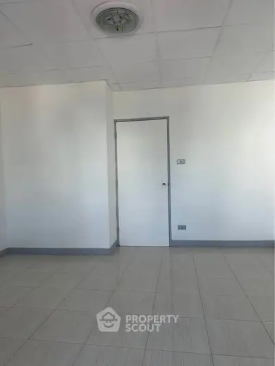 Spacious empty room with tiled floor and white walls, ideal for customization.