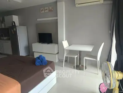 Modern studio apartment with sleek design, featuring a cozy bed, compact dining area, and efficient kitchen space.