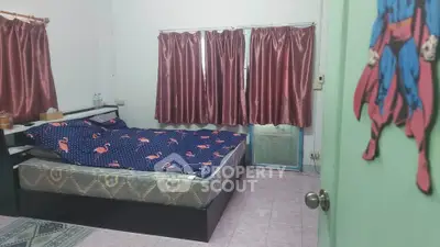 Cozy bedroom with patterned bedspread and pink curtains, perfect for a restful retreat.