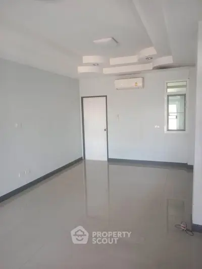 Spacious empty room with glossy tiled floor and modern ceiling design