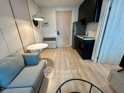 Modern compact living room with kitchenette, featuring sleek design and cozy furnishings.