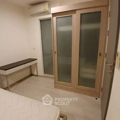 Cozy bedroom with sliding door wardrobe and air conditioning in modern apartment.