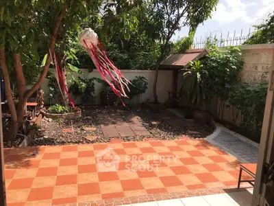 Charming garden with tiled patio and lush greenery, perfect for outdoor relaxation.