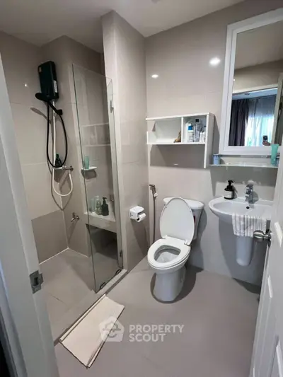 Modern bathroom with glass shower and sleek fixtures in contemporary apartment.