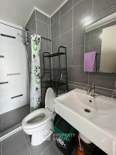 Modern bathroom with sleek design, featuring a shower, sink, and toilet in a compact layout.