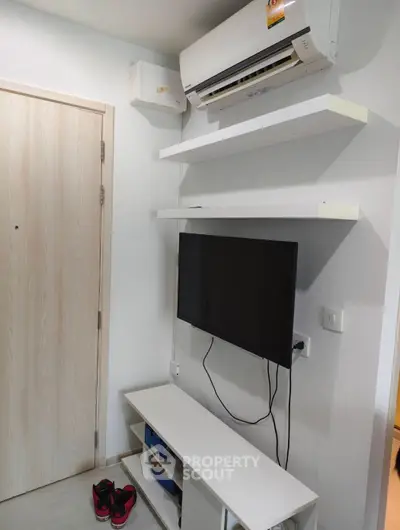 Modern living room corner with wall-mounted TV and air conditioning unit.