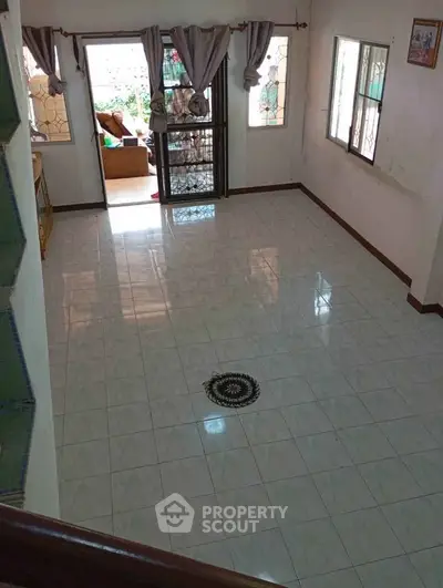 Spacious tiled living room with natural light and garden view, perfect for family gatherings.