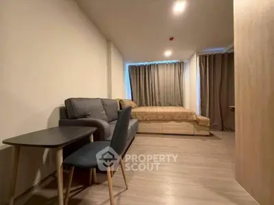 Modern studio apartment with cozy living area and bed, featuring stylish furniture and warm lighting.