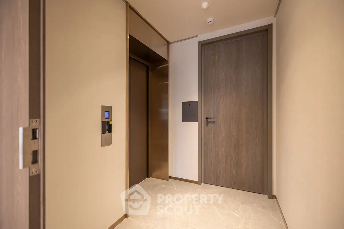 Modern apartment entrance with sleek elevator and wooden door