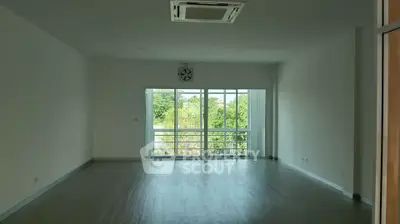 Spacious living room with large windows and greenery view, perfect for natural light lovers.