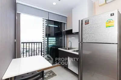 Modern kitchen with balcony view, featuring sleek appliances and ample natural light.