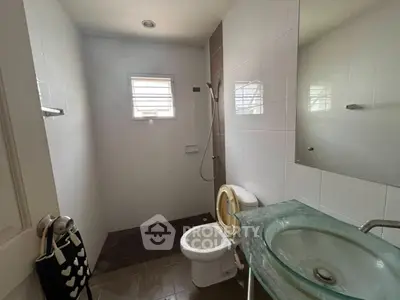 Modern bathroom with glass sink and shower in a well-lit space.