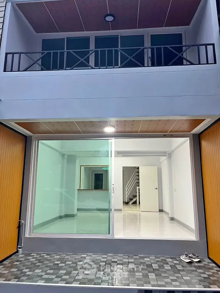 Modern townhouse entrance with glass doors and balcony, showcasing sleek design and inviting interior.