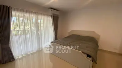 Spacious bedroom with large window and modern furnishings in a serene setting.