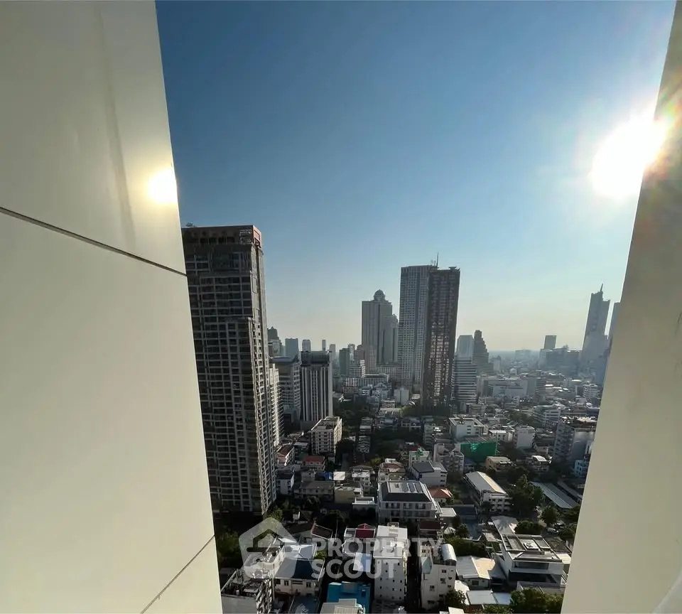 Stunning cityscape view from high-rise building balcony with clear blue sky.