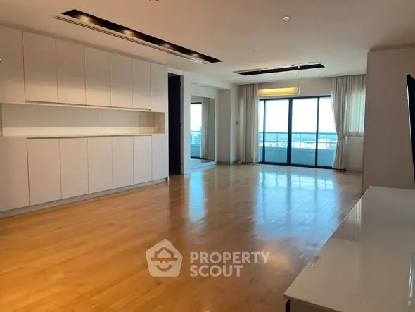 Spacious modern living room with wooden flooring and large windows offering a stunning view.