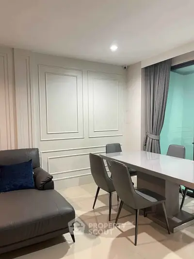 Modern dining area with sleek table and chairs, adjacent to a stylish living room sofa.