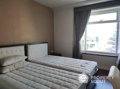 Spacious bedroom with twin beds and large window offering city view