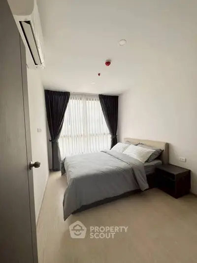 Modern bedroom with large window and stylish curtains in a minimalist apartment.