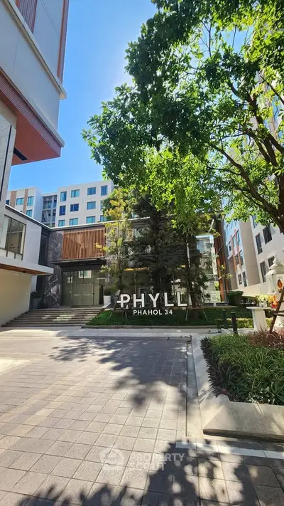 Modern condominium entrance with lush greenery and stylish architecture at Phyll Phahol 34.