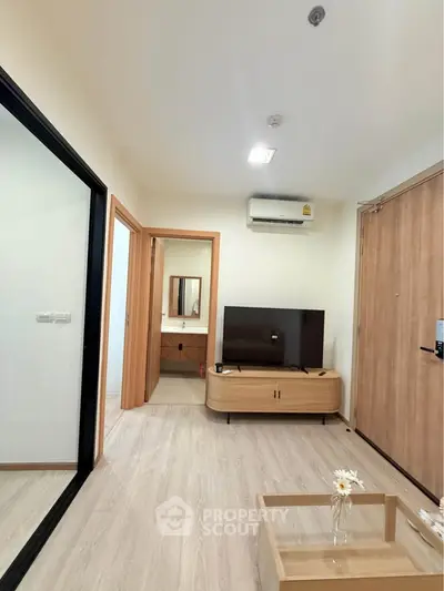 Modern living room with sleek wooden furniture and a view into a stylish bathroom.