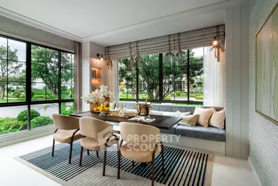 Elegant dining area with large windows and garden view, featuring modern decor and stylish seating.
