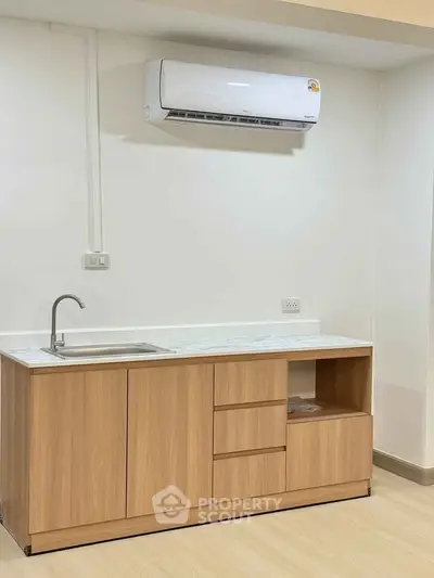 Modern kitchen with sleek wooden cabinetry and air conditioning unit, perfect for contemporary living.