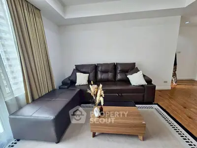 Modern living room with leather sofa, stylish coffee table, and elegant decor in a bright, spacious setting.