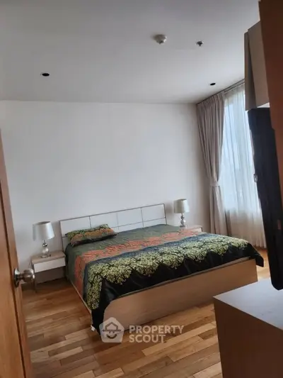 Spacious bedroom with elegant decor and large window for natural light.