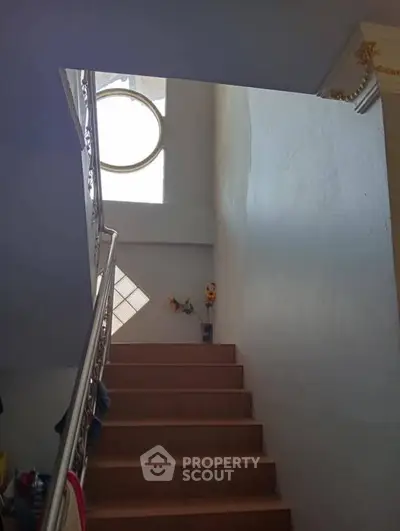 Elegant staircase with natural light and decorative railing in modern home.