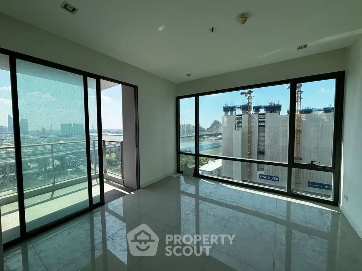 Spacious apartment with floor-to-ceiling windows and balcony offering stunning city and river views.