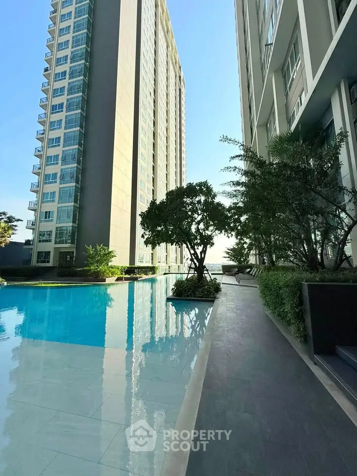 Luxurious high-rise building with serene poolside view and lush greenery, perfect for modern living.